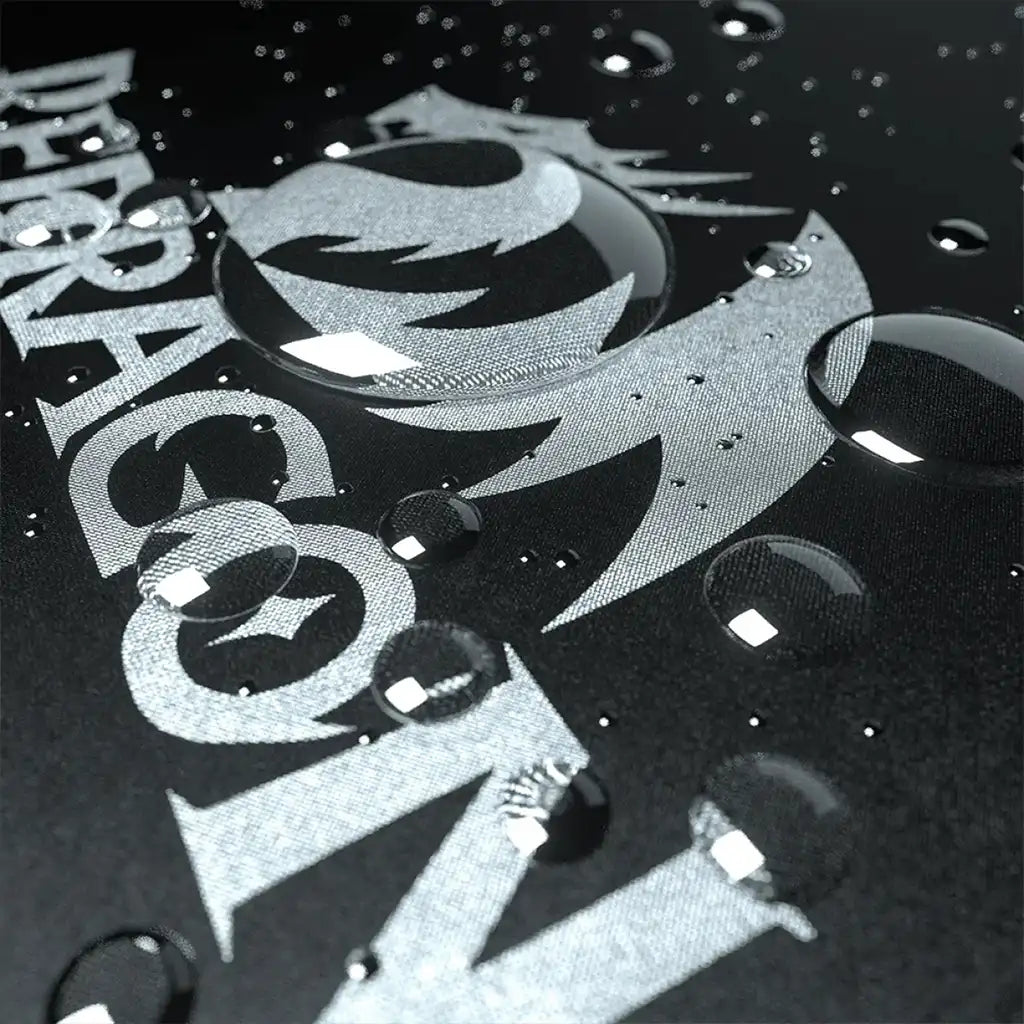 Close up of the water-resistant surface of the Redragon Flick P032 XL gaming mousepad with water droplets, showing part of the logo