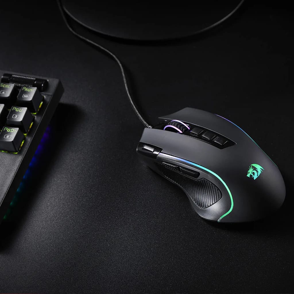Redragon M612 Predator RGB Gaming Mouse from above, positioned next to a keyboard to show scale and on-desk appearance